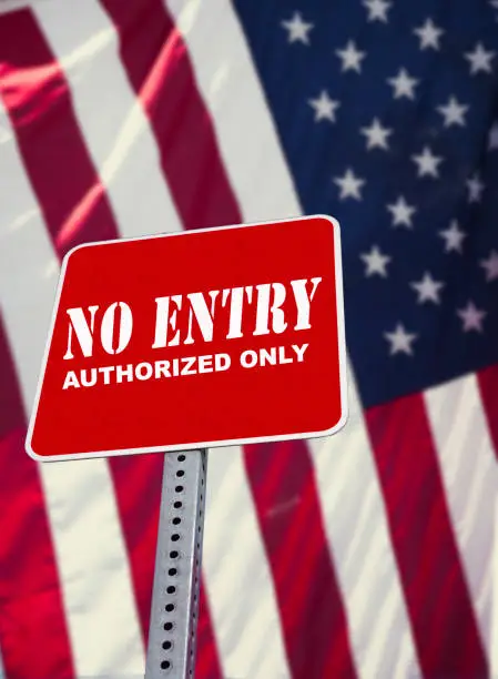 No Entry sign with USA Flag in background to illustrate the new possible immigration bans for tourists entering the USA