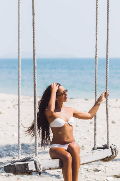 istock Girl sits on a swing on white sandy beach 641080826