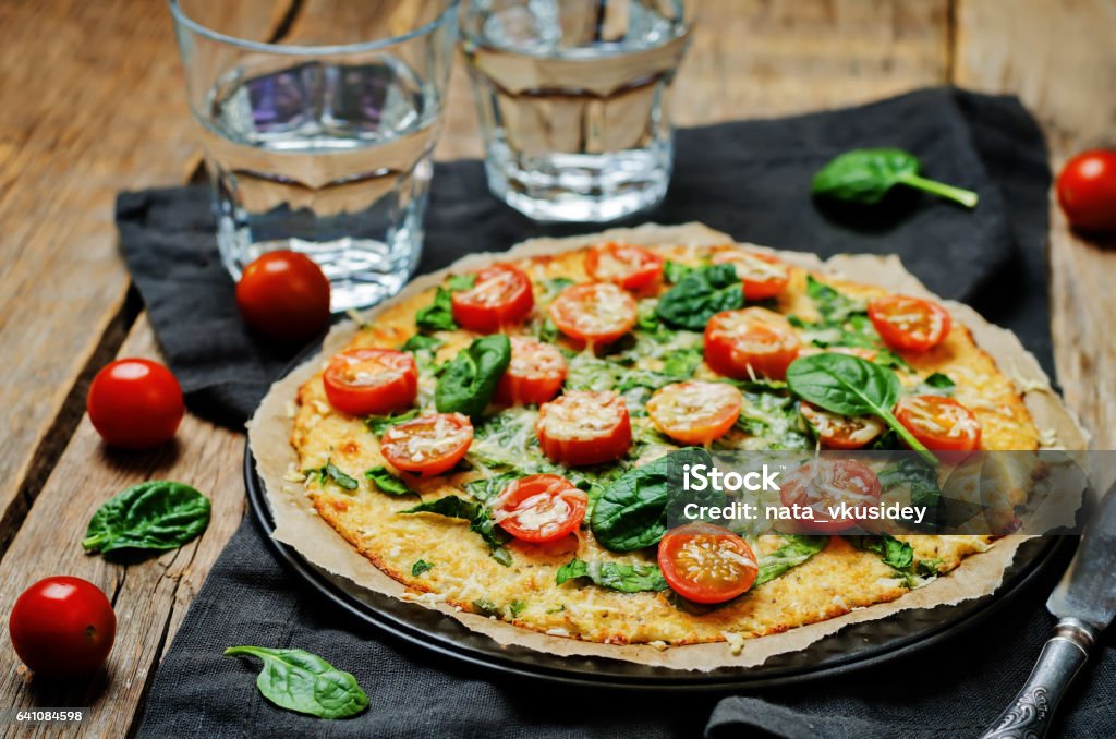 Cauliflower pizza crust with tomato and spinach Cauliflower pizza crust with tomato and spinach. toning. selective focus Pizza Stock Photo