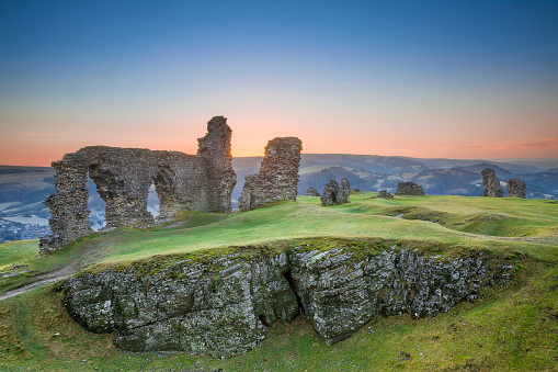 The Castell Dinas Bran, or Crow Castle in English, in Wales at sunset. These ancient ruins are all is left of a mighty castle that once stood on top of the hillside near the city of Llangollen, Wales, UK.