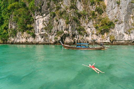 Young Caucasian woman swimming near the  Thai Taxi boat in  Krabi, Thailand