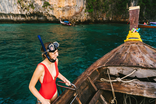 Young Caucasian woman in snorkeling mask in Thai Taxi boat in  Krabi, Thailand