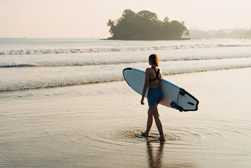Young Caucasian woman standing on the beach with surfboard, Weligama, Sri Lanka