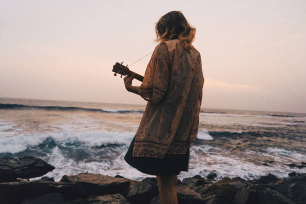 женщина играет укулеле у моря - 20s acoustic guitar adult art стоковые фото и изображения