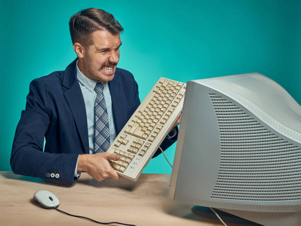 istock Angry businessman breaking keyboard against blue background 641122320