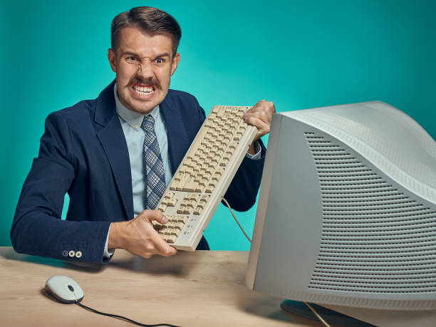 istock Angry businessman breaking keyboard against blue background 641122344
