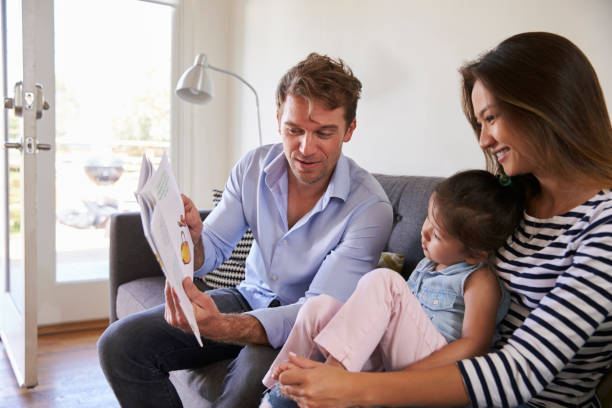 istock Parents Reading With Baby Daughter On Sofa At Home 641123252