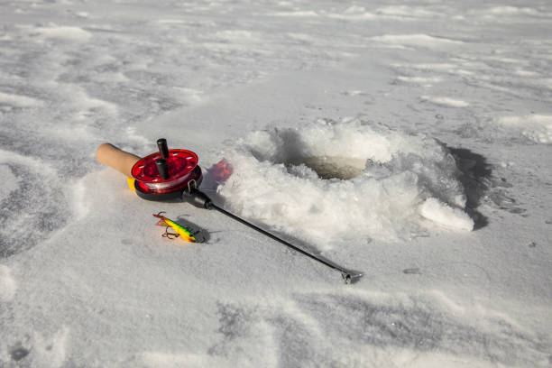 Ice fishing hole on the surface of the river in winter
