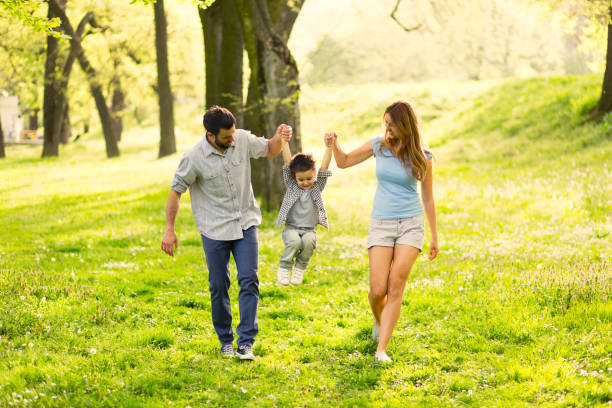 istock Playful parents holding hands and swinging small kid. 641150784