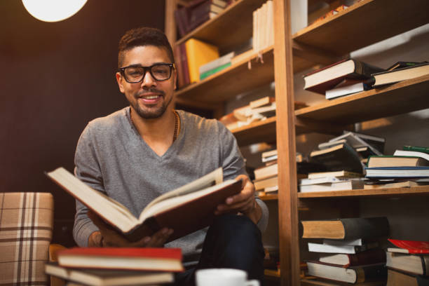 istock Smiling African American student reading a book in library. 641151556