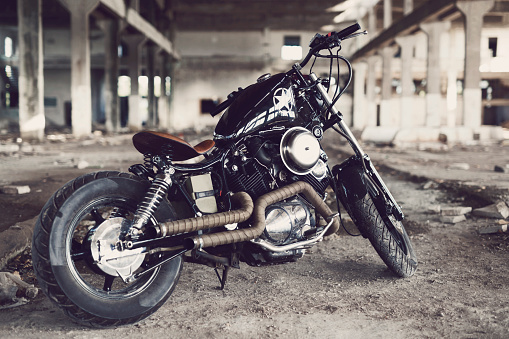 Custom made motorcycle parked in an old ruined garage.