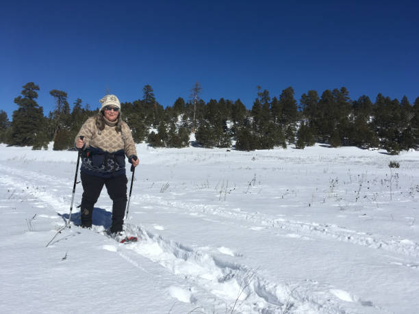 Woman Snowshoeing This senior woman is snowshoeing across a snow covered meadow in Flagstaff, Arizona, USA. jeff goulden flagstaff stock pictures, royalty-free photos & images