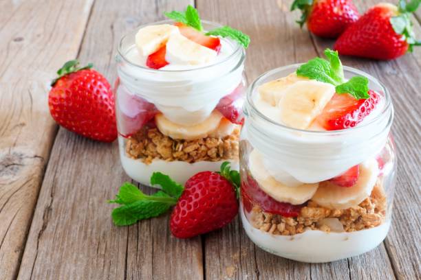 Strawberry banana parfaits in mason jars on rustic wood Healthy strawberry and banana parfaits in mason jars on a rustic wood background parfait stock pictures, royalty-free photos & images