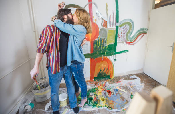 Two people, heterosexual couple, DIY, painting, kissing.