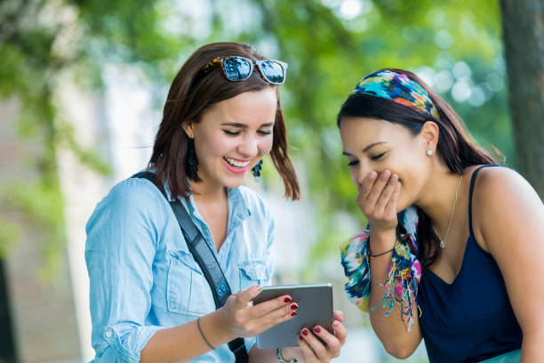 istock Female college friends laugh while looking at tablet 641168486