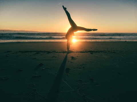 20 year old woman does yoga and gymnastics on a beautiful beach in California