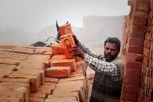 Builder trowels smears cement mortar on brick during bricklaying.