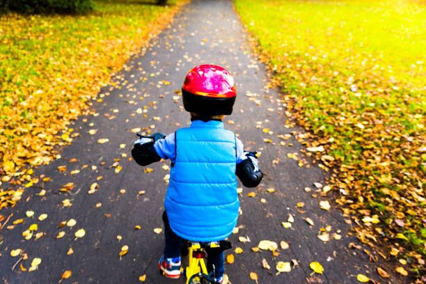 overhead-ansicht eines jungen, der im herbstpark mit dem fahrrad mit schutzhelm im freien fährt - safe ride stock-fotos und bilder