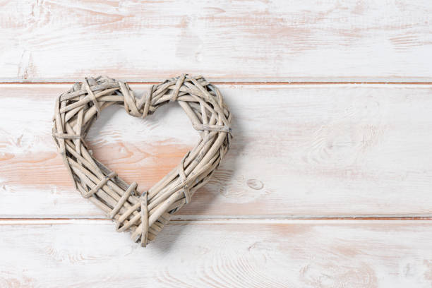 Wicker rattan heart on a white wooden panel background with copy space
