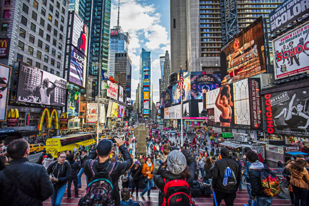 View of crowded Times Square in New York City View of crowded Times Square in New York City. People are at major commercial intersection and neighborhood in Midtown Manhattan. Commercial signs are on buildings in city. Travel Locations. times square stock pictures, royalty-free photos & images