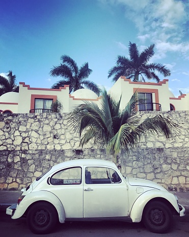Cancun, Mexico - January 2, 2017: Volkswagen Beetle parked on Cancun street. Houses and tourist resorts on background.