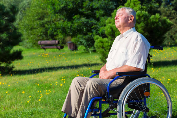 old man on wheelchair enjoying sunlight stock photo