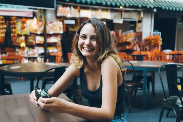 Young Caucasian woman eating food in Chinatown district in Singapore