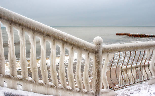 ice covered fence on the beach on cold gloomy winter day