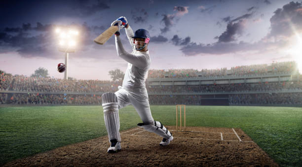 Cricket: Batsman on the stadium in action Cricket bouncing a ball on a cricket field. The batsman is wearing unbranded sports cloth and equipment. The bleachers full of people are blurred behind the player. Background is made in 3D. There are intentional lenseflares on the image. batsman photos stock pictures, royalty-free photos & images