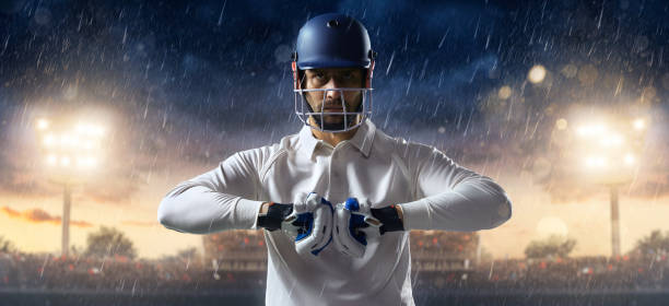 Cricket: Batsman on the stadium in action Cricket player standing on a cricket field. The batsman is wearing unbranded sports cloth and equipment. The bleachers full of people are blurred behind the player. Background is made in 3D. There are intentional lenseflares on the image. batsman photos stock pictures, royalty-free photos & images