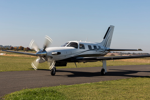 Private small single turboprop aircraft on airport runway. Small sports plane scrolls on the runway on a sunny day