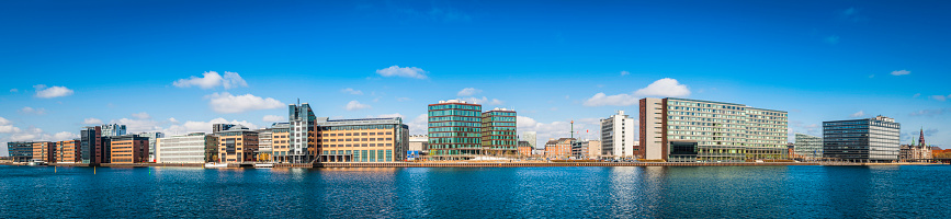 Panoramic view across the blue harbour waterfront to the modern office buildings, hotels and apartment blocks of Copenhagen, Denmark's vibrant capital city.