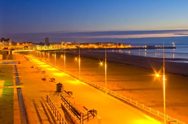Sunrise over the South Bay and Harbour at Bridlington, East Riding of Yorkshire. Flamborough Lighthouse can be seen above the light on the end of the pier.