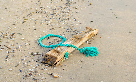 Rope in knots, lying on sandy beach. Copy space.
