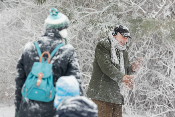 Group of friends having fun on snow. Having a snowball fight. Wearing warm clothing.