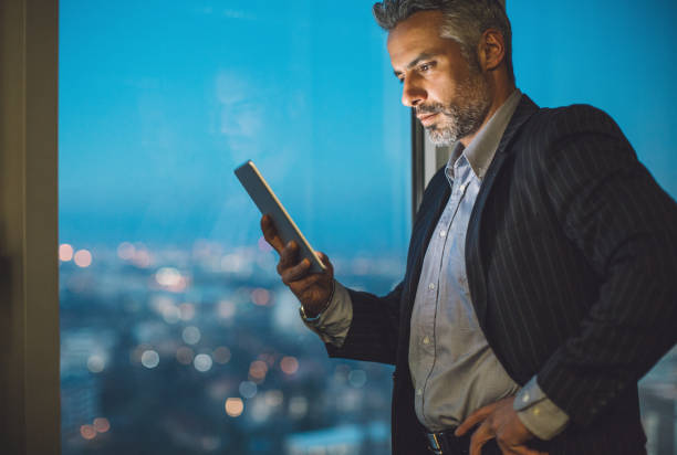 istock Middle aged businessman with digital tablet at night 641197260