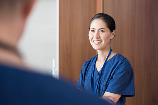 Cheerful nurse in uniform looking at colleague