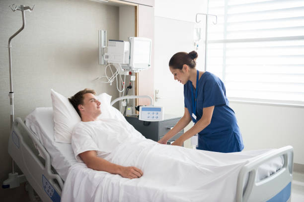 Young man in hospital bed with nurse by his side
