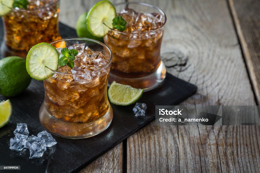 Rum and cola cocktail in glasses Rum and cola cocktail in glasses, rustic wood background Cola Stock Photo