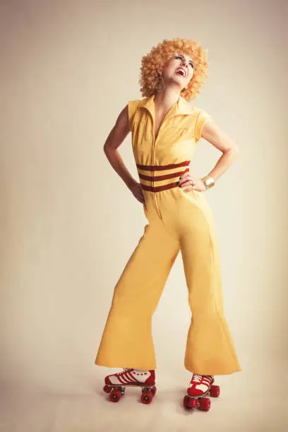 A retro 70's woman wearing a bell bottom jumpsuit and roller skates.