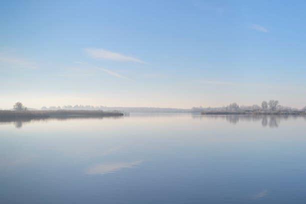 Frozen island in the distance in the middle of a calm winter lake landscape during a beautiful cold day.