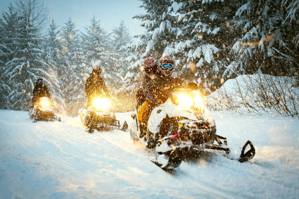 Couple snow mobile in snow storm Snow mobile in blizzard through the woods and forest cold-climate-forest stock pictures, royalty-free photos & images