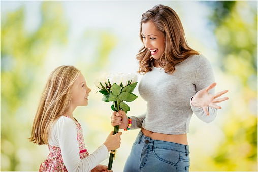Cute daughter giving her mother Bouquet white roses for Mother's Day.