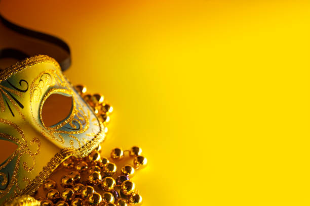 Gold feather masquerade mask isolated on white with copy space in a beaded frame.