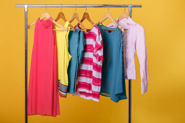 istock colorful womens clothes on hangers on rack on orange background. 641220298