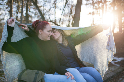 Two young woman sitting on a bench in park