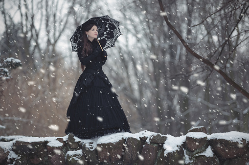 Woman in black Victorian dress in the winter park