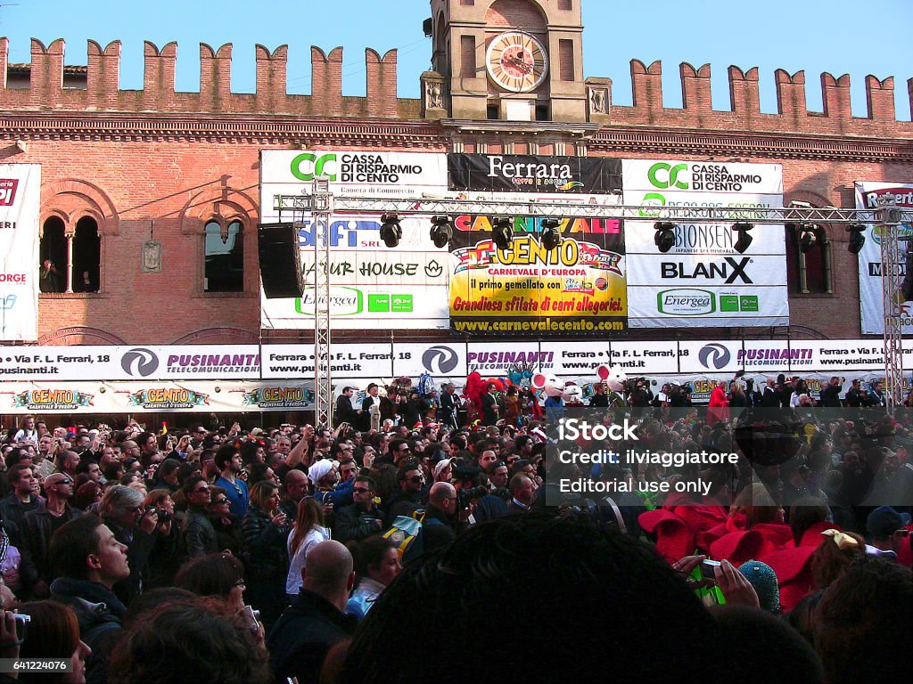 Cento, Emilia-Romagna, Italy - march 6, 2011: in the main square, crowd of spectators and dancers in red costume. Near the town hall, under the installation for lights, the stage for the awards. Many recognisable people and advertising posters. this photo was taken in the town of Cento, on a sightseeing tour on 6 march 2011. All my photos  at the famous Carnival in Cento was taken on 6 march 2011. I was in the crowd with the camera raised high to overcome the heads of the other spectators. Carnival - Celebration Event Stock Photo