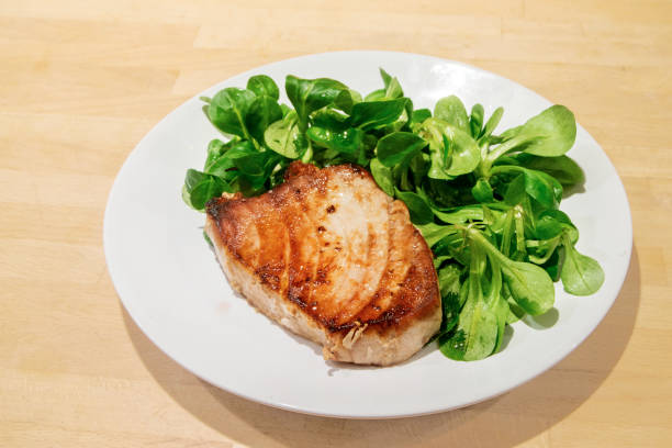 bistecca di tonno con insalata su piatto bianco, sfondo di legno - tuna steak fillet food plate foto e immagini stock