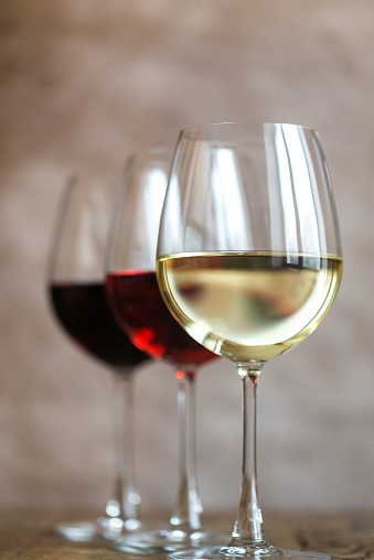 Glasses of red, rose and white wine on the wooden background